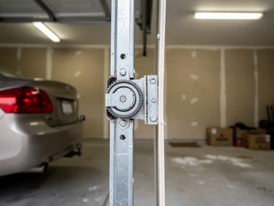 A garage door roller is attached to the vertical track.